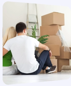 Paar sitzt zwischen gepackten Umzugskartons